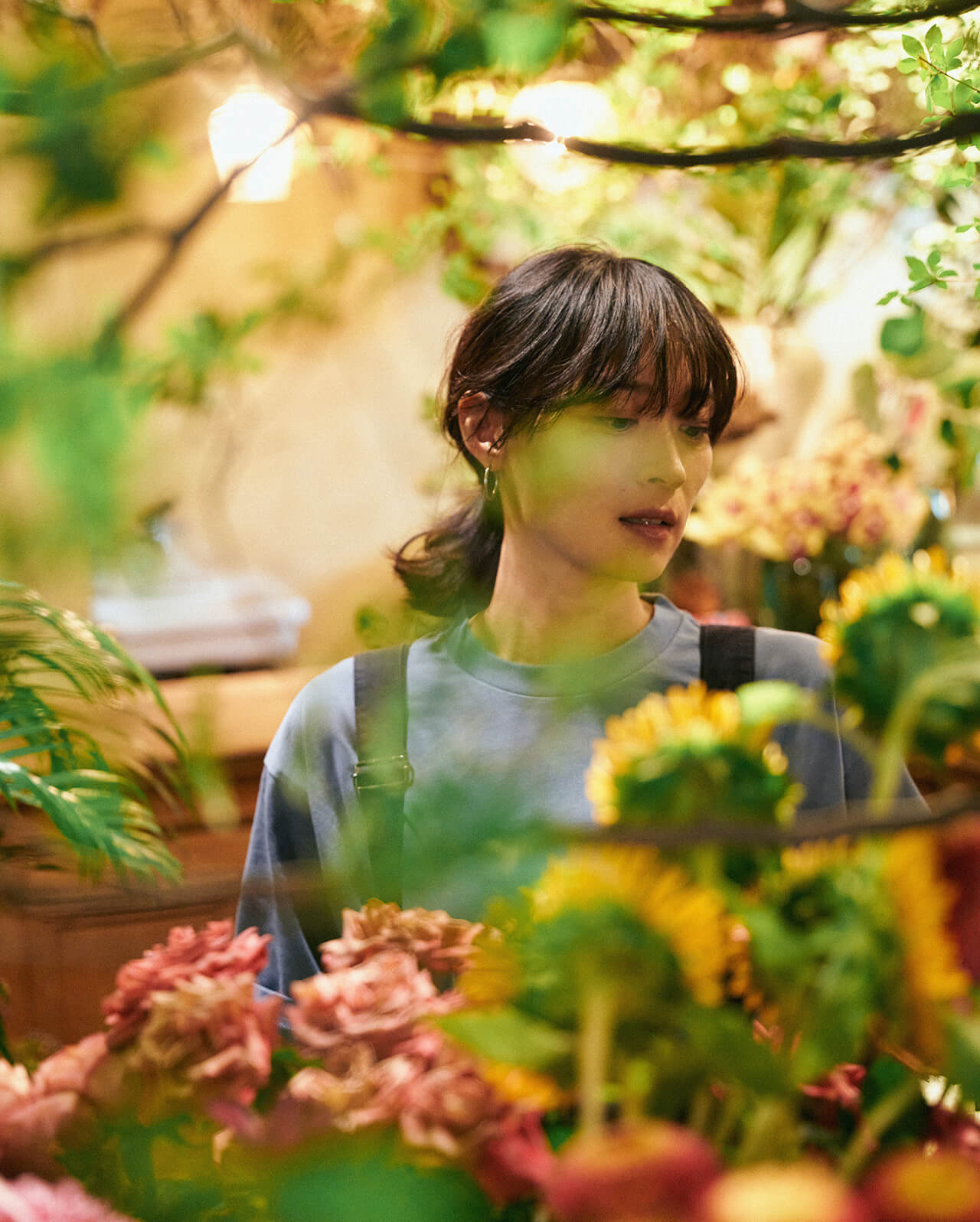 ライトブルーのトップス・ネイビーのボトムスを着用した女性がお花を選んでいる様子