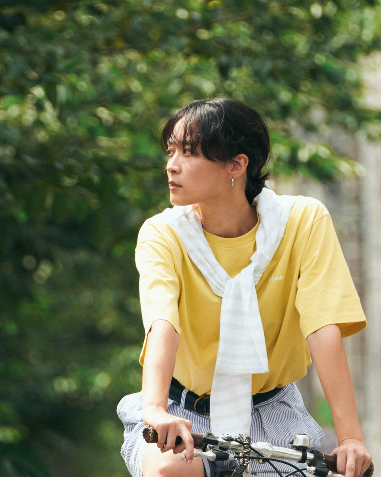 イエローのトップス・ボーダーのハーフパンツを着用した女性が自転車を乗っている様子