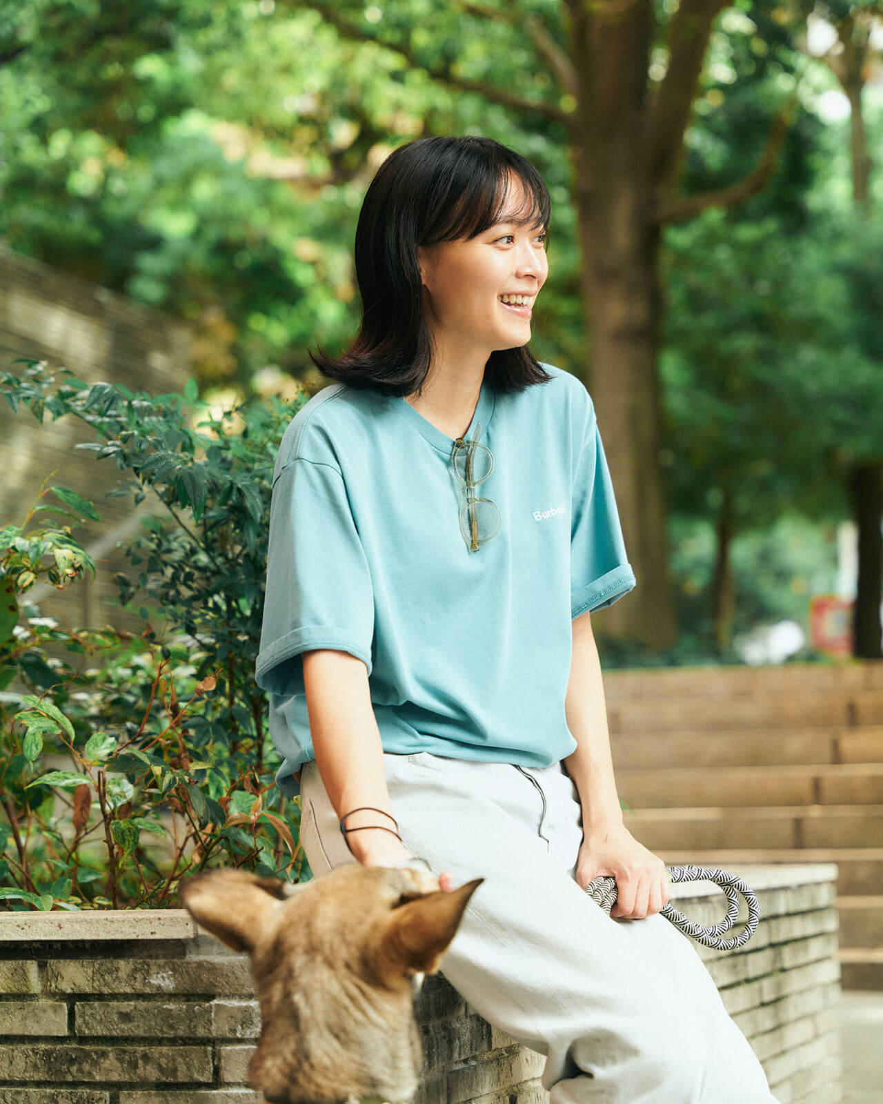 ライトブルーのトップス・デニムパンツを着用した女性が犬と休憩している様子